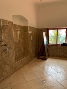 uma grande casa de banho com um chuveiro e uma janela em David Livingstone's Home em Zanzibar