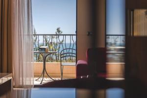 a room with a balcony with a view of the ocean at Hotel & Apartments HEC Residence in Sveti Stefan