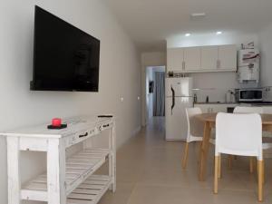 a kitchen with a white table and a television on a wall at Departamentos Apart PM in Necochea