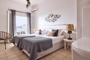a white bedroom with two beds and a window at Capetan Giorgantas in Adamas