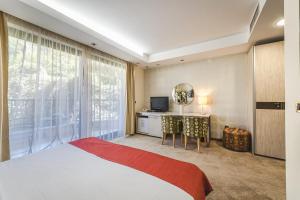 a bedroom with a bed and a desk and a television at Hotel & Apartments HEC Residence in Sveti Stefan
