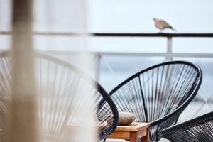 ein Paar Stühle auf einem Balkon mit einem Vogel auf dem Dach in der Unterkunft Capetan Giorgantas in Adamas