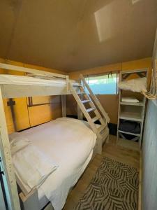 Pokój z 2 łóżkami piętrowymi i dywanem w obiekcie Glamour Glamping at little beach w mieście Jabbeke