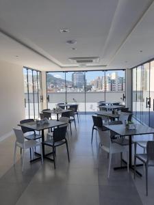 a dining room with tables and chairs and windows at Edifício ABEPOM in Florianópolis