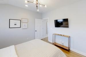 een witte slaapkamer met een bed en een flatscreen-tv bij Sweetbrier Serenity in Nashville