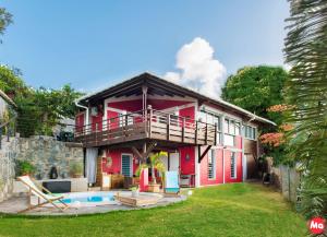 a red house with a balcony and a pool at Villa Hawa in Koungou