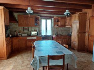 a kitchen with a blue table and wooden cabinets at Maison au coeur de la campagne jurassienne in Beauvoisin