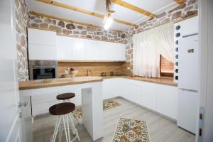 a kitchen with white cabinets and a stone wall at Villa Kadiu in Korçë
