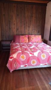 Una cama con un edredón rosa y blanco. en Casa los Lobos a una cuadra de la playa El Quisco, en El Quisco