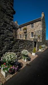 um edifício de pedra com flores em frente em The Lodges @ Barra Castle em Inverurie