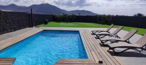een zwembad met 2 stoelen en een golfbaan bij Villa Geneva - Relax y diversión in Playa Blanca