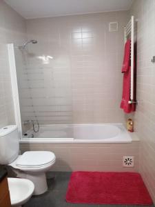 a bathroom with a white tub and a toilet and a red rug at CASA VISTA RIO ESPOSENDE in Esposende +9 photos