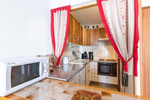 eine Küche mit roten Vorhängen und einer Mikrowelle in der Unterkunft Apartment with Balcony and View in Le Grand-Bornand