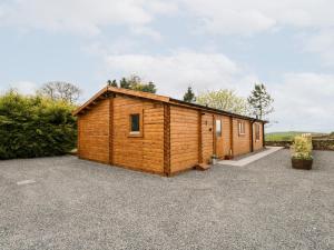 a wooden cabin in a gravel parking lot at Howgill Lodge in Kendal