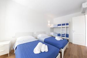 two beds in a bedroom with blue and white at Sardinia Gold Luxury Apartment in Palau