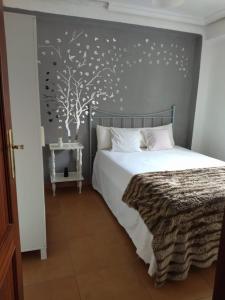 een slaapkamer met een bed en een muurschildering van bomen bij Santa Justa in Sevilla