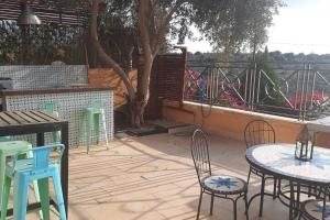 a patio with tables and chairs and a tree at La Villa Toscana: Pool & Elah Valley vineyard view in Adderet