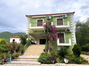 a green house with stairs and flowers at Harmony resort in Parga