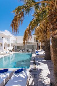 a swimming pool with palm trees and lounge chairs at ILIADA-ODYSSEAS RESORT in Perivolos