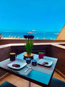 un tavolo con due piatti di cibo e fiori su un balcone di Una finestra sul Blu a Teulada