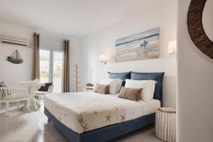 a white and blue bedroom with a bed and a chair at Capetan Giorgantas in Adamas