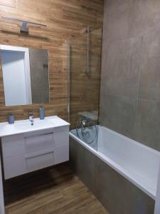 La salle de bains est pourvue d'un lavabo, d'une douche et d'une baignoire. dans l'établissement Apartamenty Termalne na Długiej 6, à Uniejów