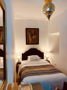 Un dormitorio con una cama grande y una lámpara de araña. en Riad Ajmal, en Marrakech