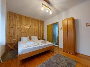 a bedroom with a bed with a wooden wall at Fenyőfa vendégház in Szilvásvárad