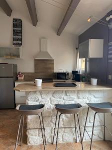 ル・バルカレスにある100m de la plage, villa 4pers, clim, secteur grande plageのカウンターとその前に3脚の椅子があるキッチン +4枚の写真