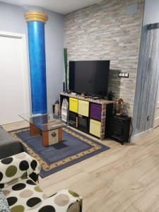 a living room with a flat screen tv on a brick wall at Centro de Baracaldo, parcela de garaje gratis in Barakaldo