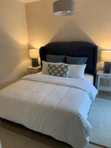 een slaapkamer met een groot wit bed met 2 lampen bij Divine Meteora Luxury midtown apartment in Kalabaka