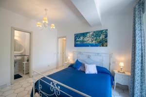 a bedroom with a blue bed and a bathroom at YourHome - Relais Casa degli Angeli in Positano