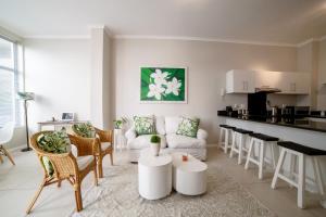 a living room with white furniture and a kitchen at Spacious Surfers Corner Beach Apartment in Cape Town
