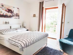 ein Schlafzimmer mit einem Bett, einem Stuhl und einem Fenster in der Unterkunft Josipa & Jelena Apartment in Senj