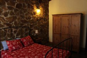 1 dormitorio con cama y pared de piedra en Casas Rurales Las Cuevas El Rincón, en Fuentes de León