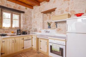 a kitchen with white appliances and a stone wall at Strofilia Authentic Villas in Skinária