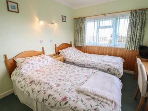 een slaapkamer met 2 bedden en een raam bij Morlyn Guest House Apartment in Harlech