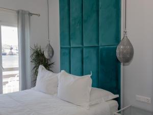 a bedroom with a white bed with a blue headboard at DIIO Suites in Ermoupoli