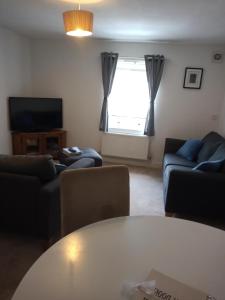 ein Wohnzimmer mit Sofas, einem Tisch und einem TV in der Unterkunft The Eaves, Glastonbury High Street in Glastonbury