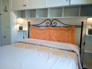 a bedroom with a large bed with an orange pillow at La spiaggetta Maladroxia in Maladroscia
