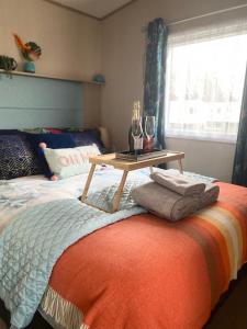 a bed with a table on it with glasses on it at Prestige caravan,Seton Sands holiday village, WiFi in Port Seton
