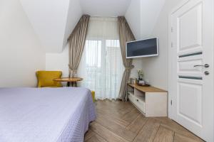 Un dormitorio con una cama, un escritorio y un televisor. en Palanga Deluxe 2, en Palanga
