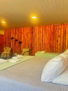 1 dormitorio con 2 camas y pared de madera en Estalagem e Restaurante Cantinho Bistrô, en Caparaó Velho