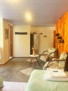 ein Wohnzimmer mit Stühlen, einem Tisch und einer Tür in der Unterkunft Estalagem e Restaurante Cantinho Bistrô in Caparaó Velho