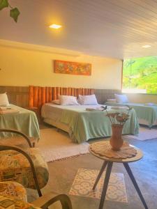 ein Schlafzimmer mit 2 Betten und einem Tisch mit einer Vase in der Unterkunft Estalagem e Restaurante Cantinho Bistrô in Caparaó Velho