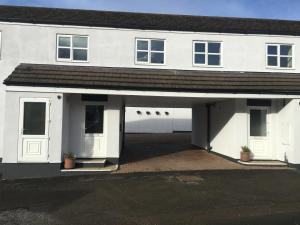 a white house with a garage with two windows at The Bullshead, Arthingworth House B&B in Market Harborough