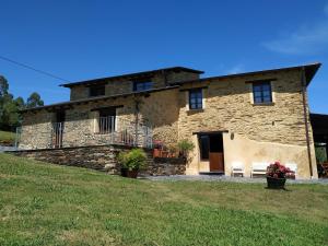ein Steinhaus mit einer Bank davor in der Unterkunft Casa Carballeira in Villarfernando