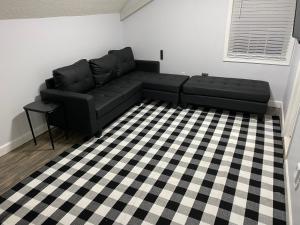 Un sofá negro en una sala de estar con suelo a cuadros. en Birthday House, en Columbia