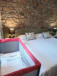 1 dormitorio con 2 camas y pared de piedra en Hotel Eutimio en Lastres