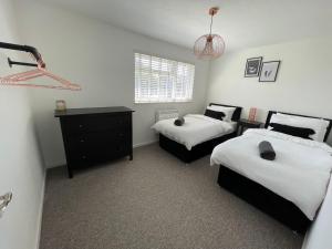 a bedroom with two twin beds and a dresser at High Tide House in Christchurch